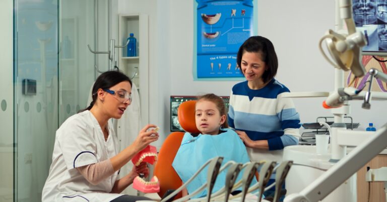 Pediatric dentist performing a childrens dental exam on a young child with parent present